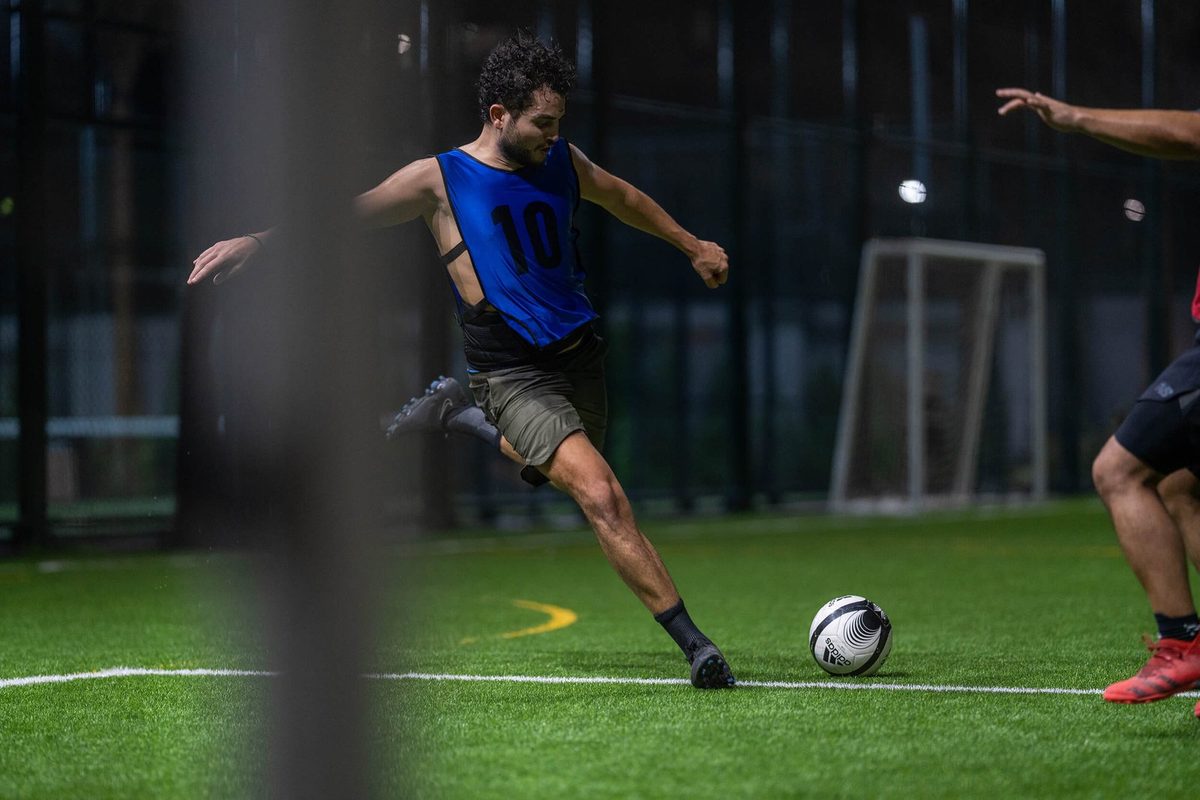 A player striking the ball on the floodlit five-a-side pitch