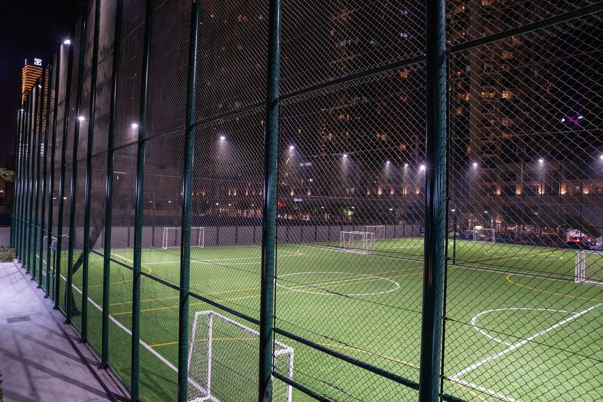 The Ballers pitches at dusk behind the cage, the Downtown Dubai skyline lit beyond