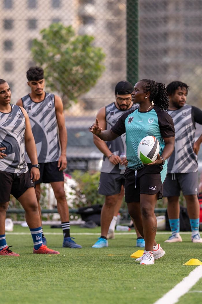 A rugby squad in a drill on the turf, the coach holding the ball